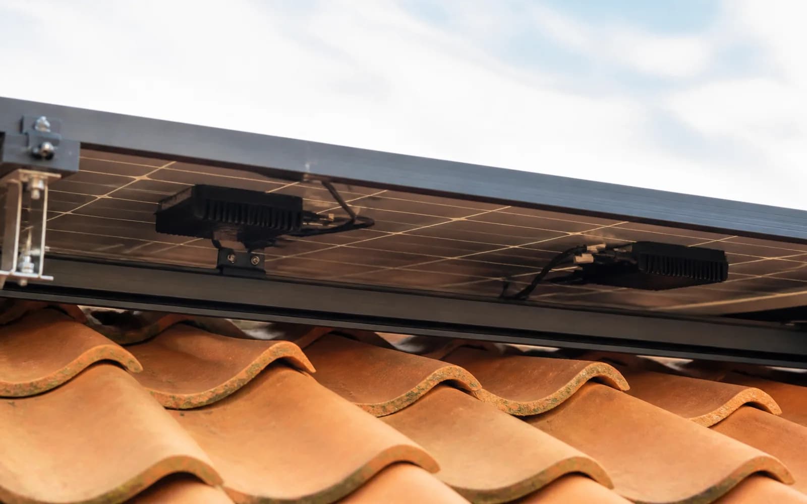 Zonnepanelen op het dak met omvormerhardware zichtbaar onder de panelen