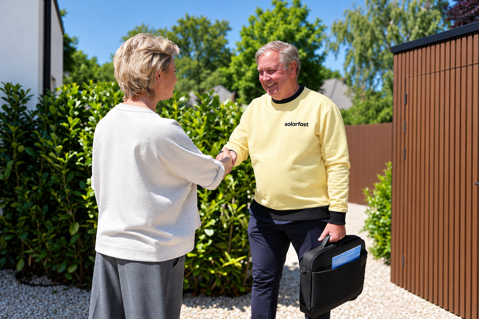 Een SolarFast-adviseur en een bewoner schudden elkaar de hand in de tuin